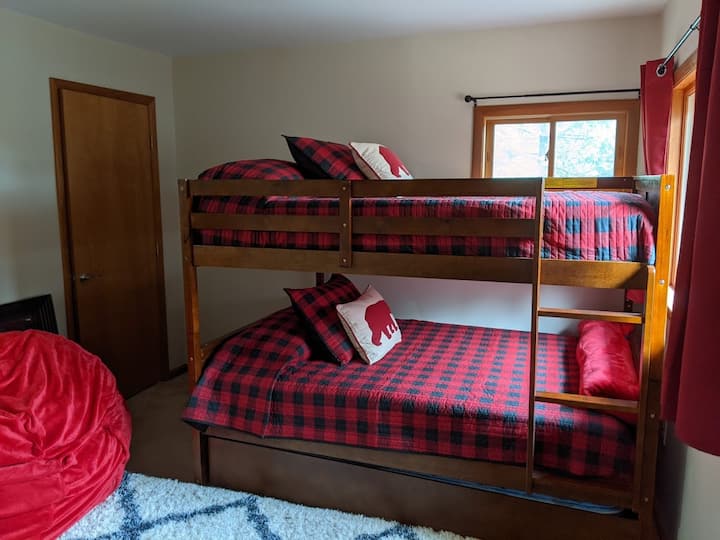 חדר קומותיים עם שתי מיטות יחיד וכיסא פופים גדול.