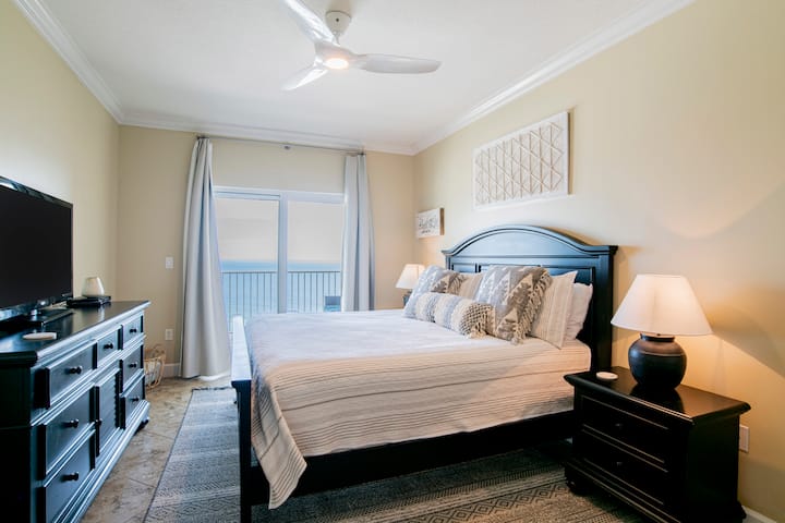 Основна спалня с изглед към океана и достъп до балкон.