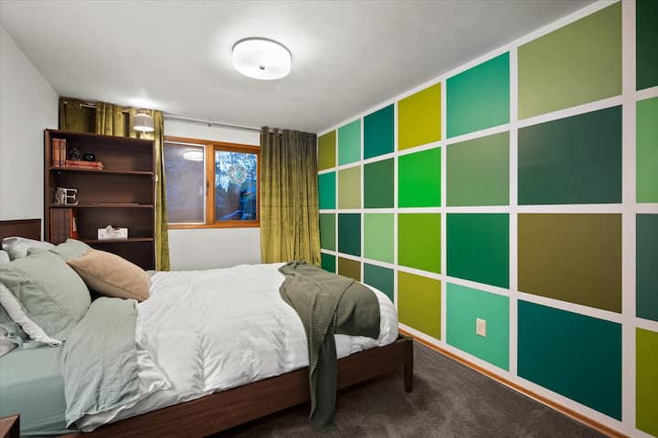 ห้องนอนมีเตียงควีนไซส์โต๊ะข้างเตียงออตโตมันชั้นวางหนังสือและตะขอ 2 -3 อันบนผนังสำหรับแขวนเสื้อผ้า