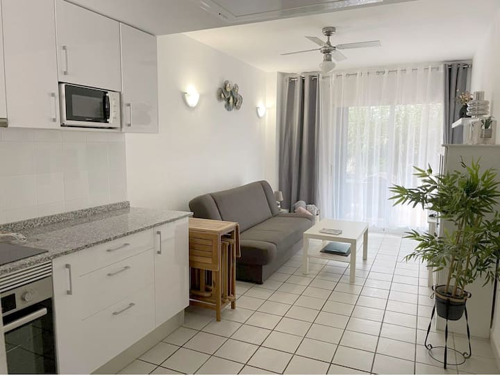 Living room with direct access to the terrace. The living room has a double sofa bed, a fold-out table with chairs for 4 people, and a smart TV. There are lots of books in the cabinet.