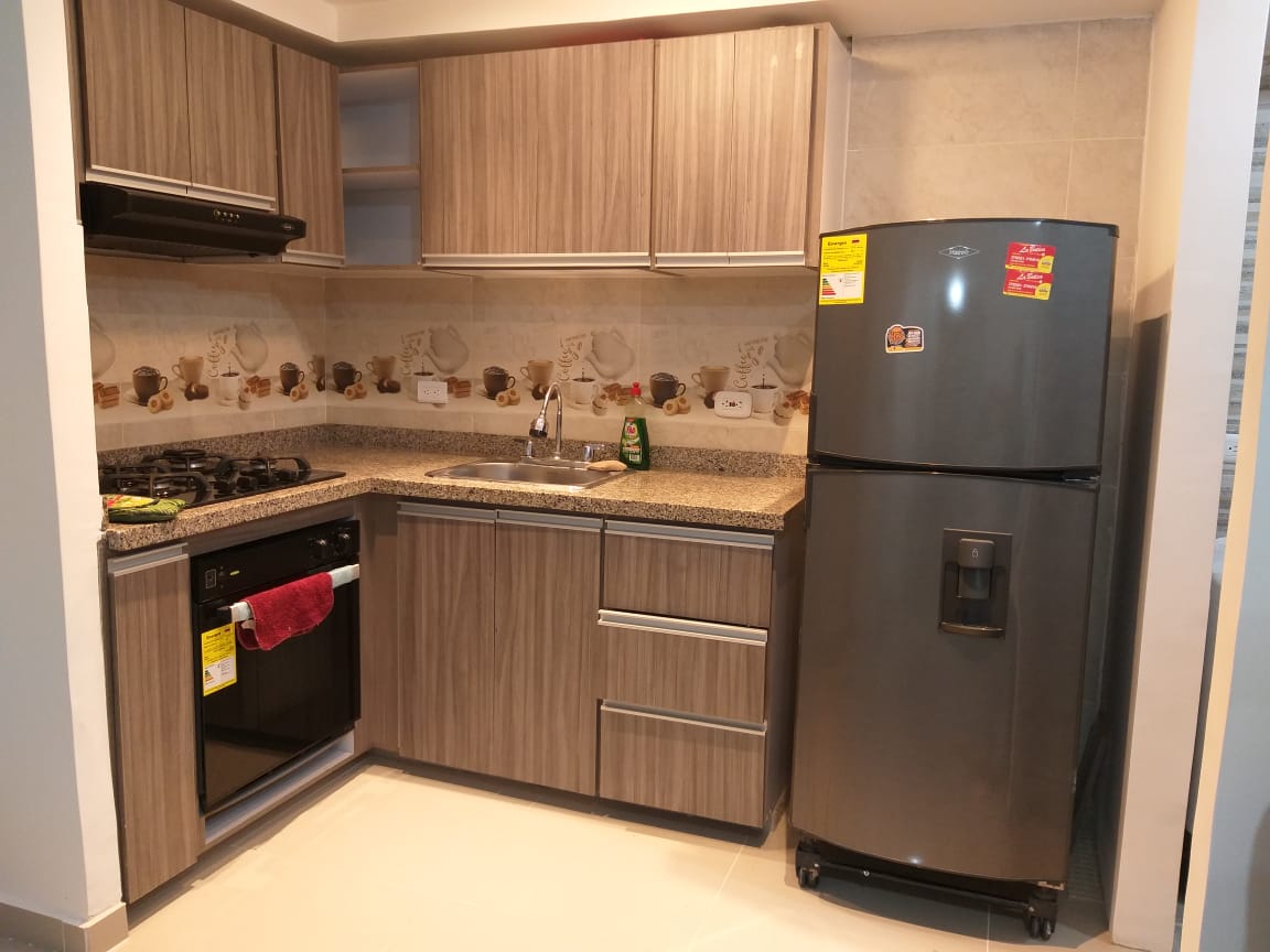 The kitchen features modern cabinetry and a granite countertop. It includes a stove, refrigerator, and dishwasher. The walls are adorned with a light-colored backsplash, enhancing the functional and organized workspace.