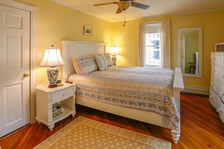 An inviting downstairs guest bedroom  features a queen-sized bed and a short, same-floor walk to the kitchen, living room, and downstairs shower/bathroom.