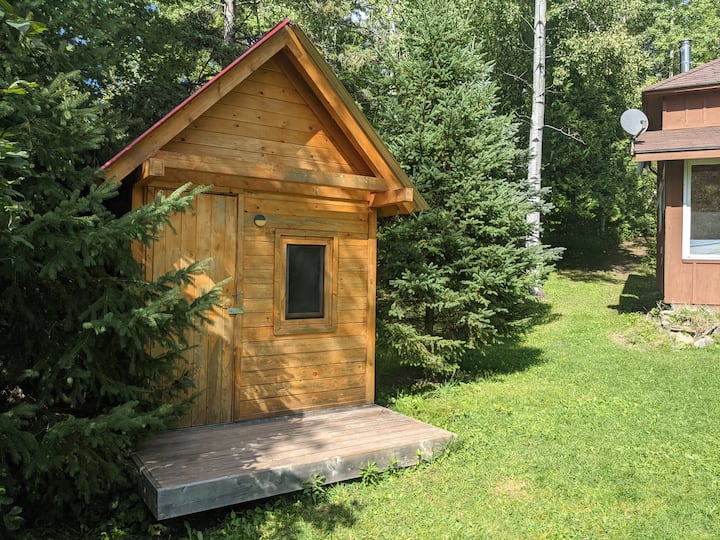 Découvrez une retraite cachée dans le Red Roof Bunkie, niché au milieu des arbres pour une escapade privée.