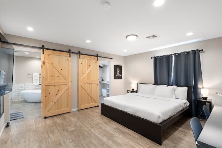 חדר שינה ראשי עם מיטת קינג סייז, שולחן גדול עם שני כיסאות, טלוויזיה חכמה ודלתות אסם שמובילות לארון הכניסה וחדר הרחצה הצמוד!