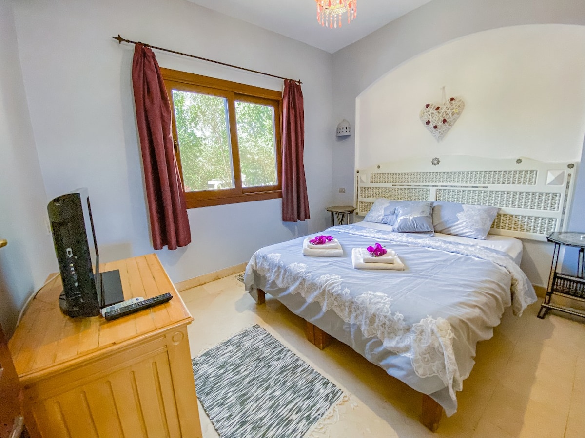 Schlafzimmer mit Doppelbett und Fernseher