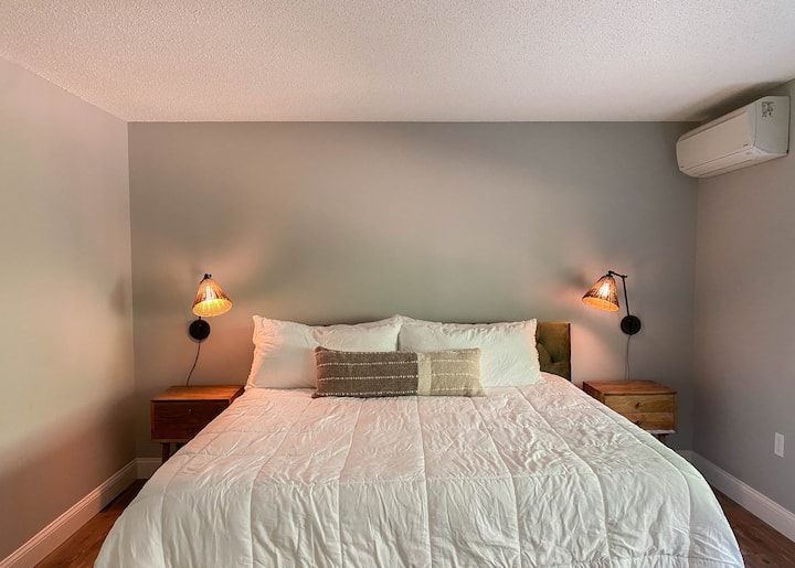 Second floor primary bedroom with king size bed and adjustable reading lamps and mini split heating and cooling.