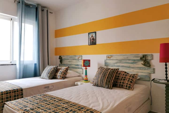 Спалня с две единични легла, гардероб и вентилатор на тавана.