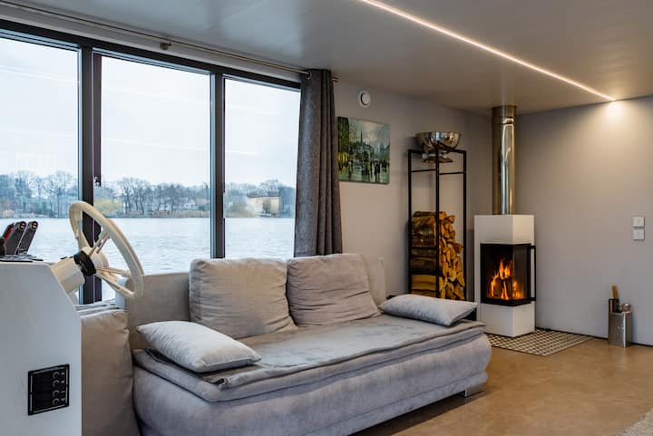 Zonë e madhe ndenjjeje me oxhak dhe një divan-krevat të rehatshëm me jastëkë me susta