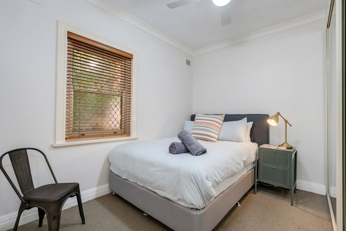 Spálňa veľkosti Queen s kvalitnou posteľnou bielizňou, zrkadlovým šatníkom a stropným ventilátorom. K dispozícii je cestovná detská postieľka a vysoká detská stolička. 