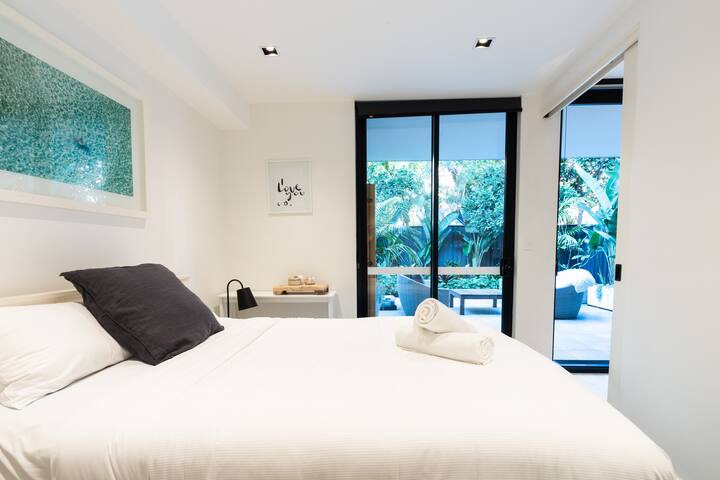 Come evening, retreat to a immaculate bedroom that’s furnished with a queen bed, floor-to-ceiling windows that overlook the courtyard, built-in wardrobes and modern artwork.