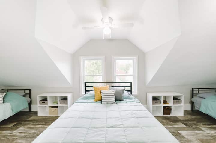 On the other side, you'll find the bunk room! This wide-open bedroom has one queen bed in the middle and one twin daybed tucked under the sloped ceiling in corner end of the room. 