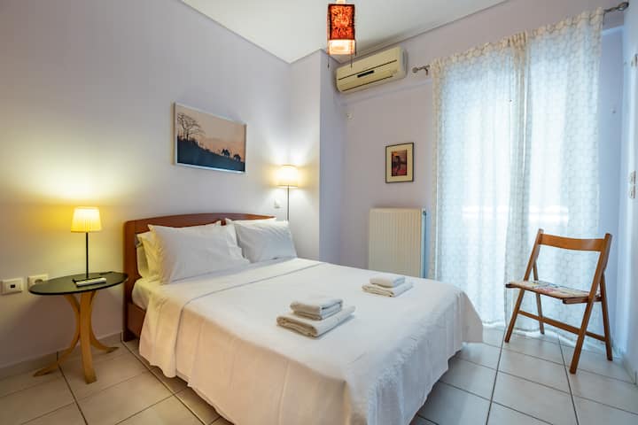 غرفة نوم مريحة وهادئة تحتوي على سرير مريح متوسط الحجم، مغمورة بالضوء الطبيعي من الستائر الشفافة. هذا المسكن الجذاب مزين بذوق رفيع بالأعمال الفنية الهادئة والإضاءة الدافئة، ويعد بليالي مريحة وملاذ هادئ.