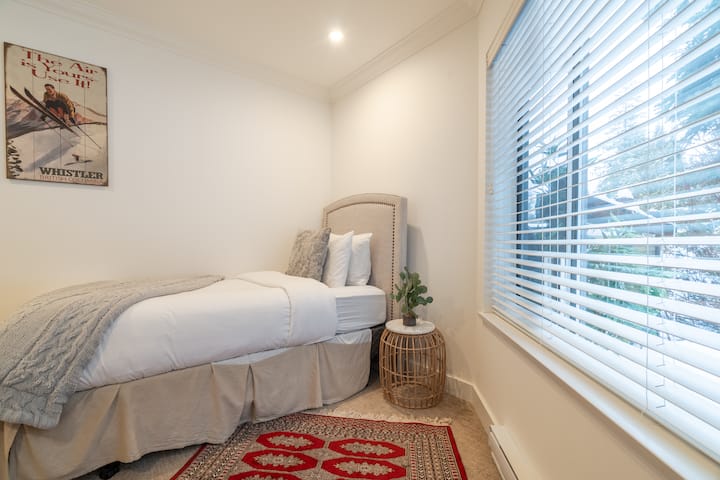 The second bedroom on the main floor features two cozy single beds and a lovely view of green space.