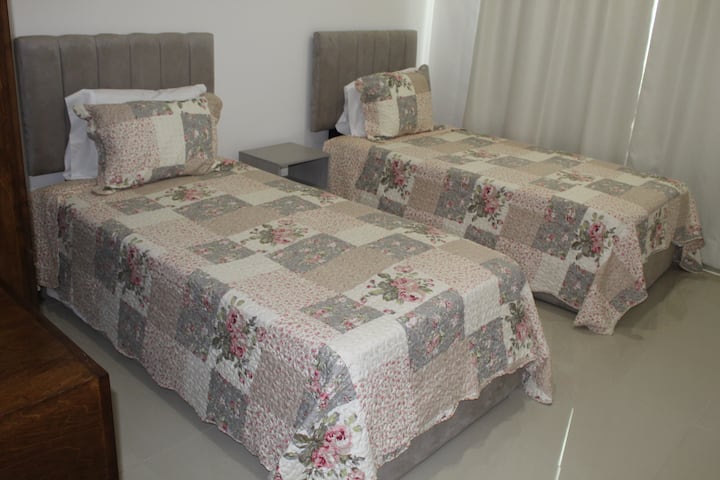 غرفة نوم بسريرين فرديين وخزانة ملابس ومكتب صغير. 