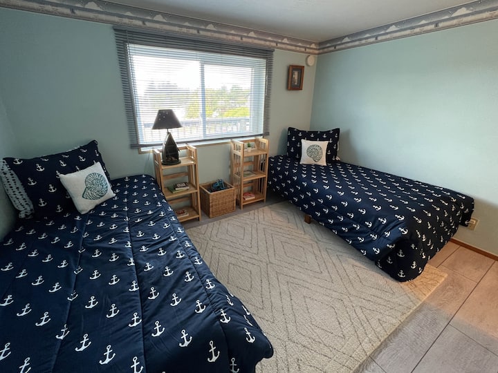 Twin beds and beds with plenty of space for playing and toys for children in baskets.  Cars, trucks, books, a large doll house and other fun toys tucked away in the closet along with a pack and play.