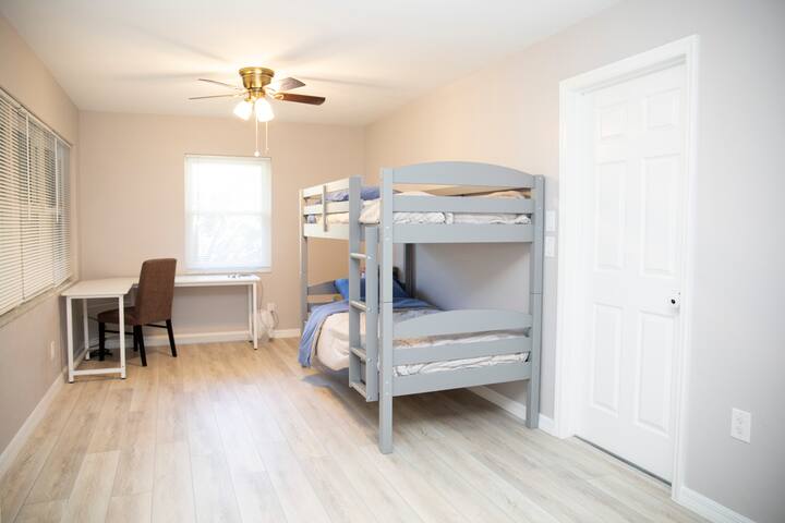 Kids Bedroom/Office: New twin trundle (memory foam), desk/chair, open closet w/toys/games. Wood-look ceramic tile, bright windows. Photos outdated, updated in April.