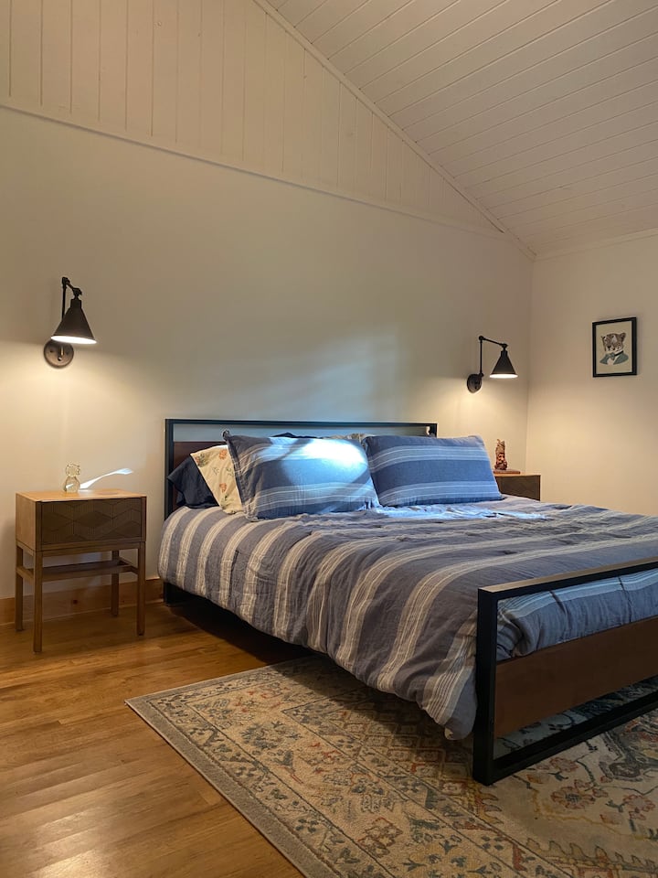 Спалната соба со големина на брачен кревет вклучува душек Tuft and Needle,  светлосни нијанси, 55-инчен паметен телевизор Samsung, простор за седење, гардеробер и гардеробер. 