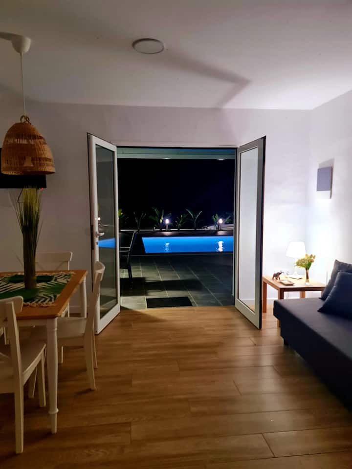 Výhľad na obývaciu izbu s bazénom a všetky vonkajšie priestory.