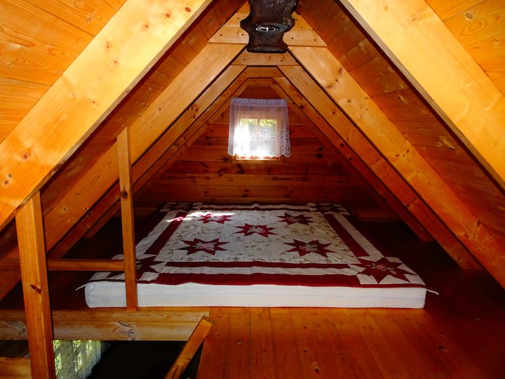En la habitación del segundo piso hay 1 cama doble y 2 camas individuales. Las ventanas están equipadas con redes meteorológicas y están disponibles para su apertura. Una lámpara colgante funciona con electricidad.