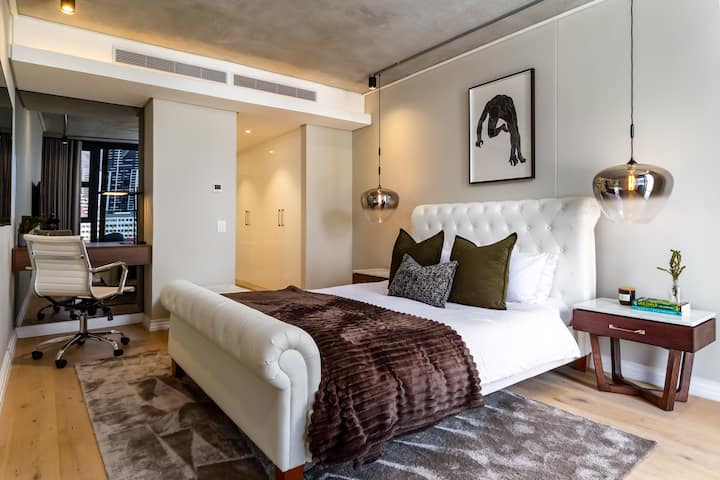 Dormitorio principal con baño privado y escritorio con silla cómoda. 