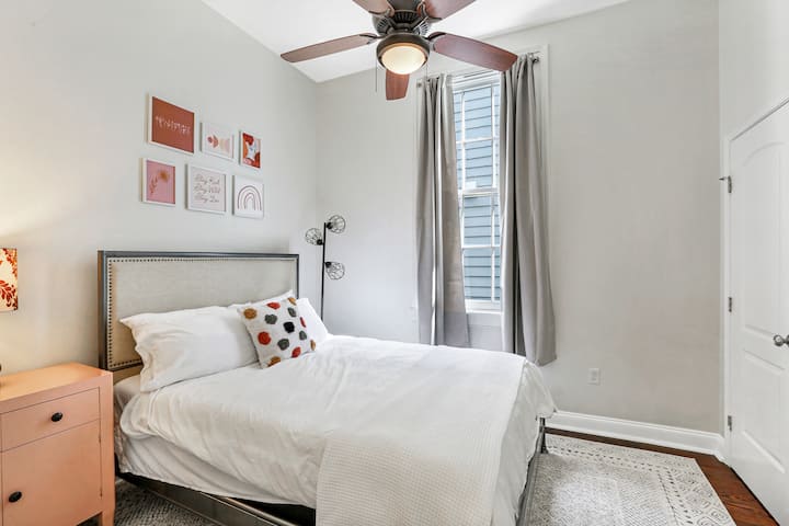 Second bedroom features a queen sized bed, smart tv, oversized window to let in plenty of natural light, a closet, and a ceiling fan to provide a peaceful breeze.