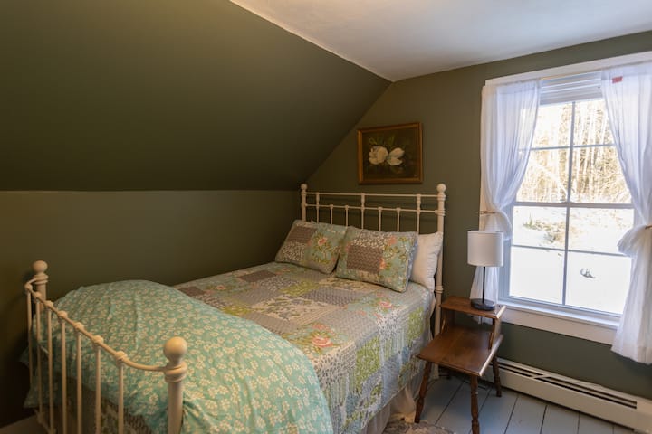 The garden room has a full size bed and view of the forest in the bask of the house.