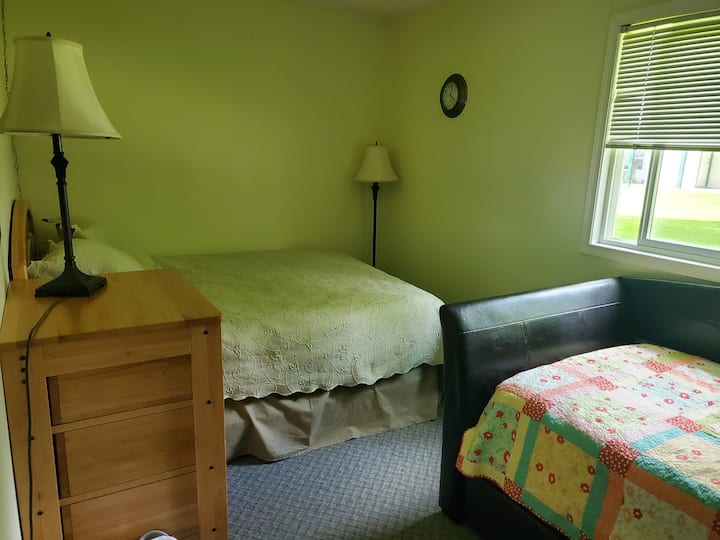 ห้องนอนชั้นล่างพร้อมเตียงควีนไซส์เตียงเดี่ยวพร้อมเตียงนอนเล่นรวมถึงตู้เสื้อผ้าและตู้เสื้อผ้า