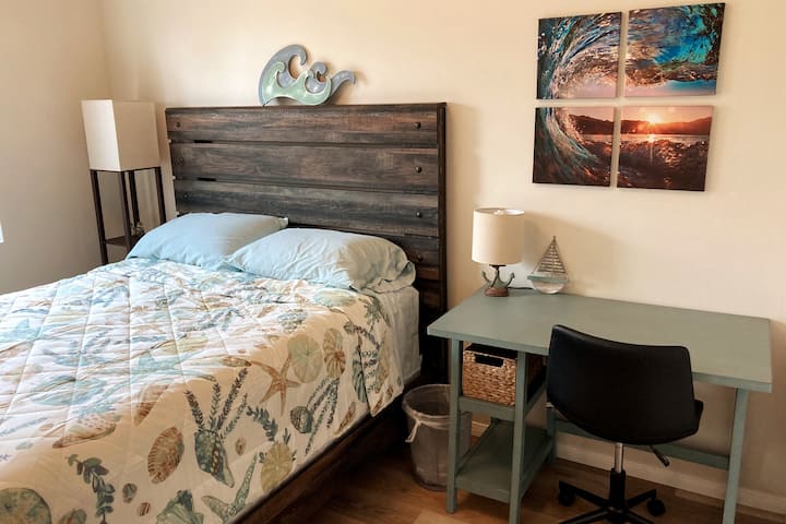 חזית: חדר שינה ראשון עם מיטת קווין סייז ושולחן כתיבה.