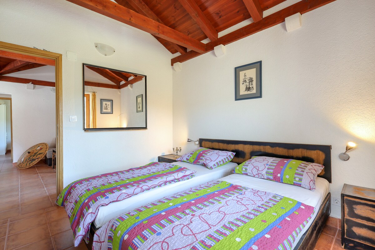 חדר שינה 1 עם שתי מיטות, שתי שידות לילה, אורות קריאה ומתלה בגדים.