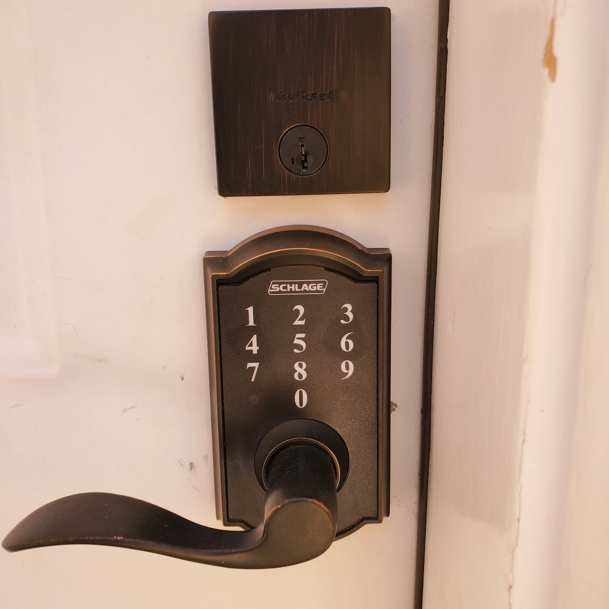 A close-up of a secure entry door lock is displayed, featuring a keypad with numeric buttons and a traditional lever handle. The sleek design and modern finish indicate a high level of security for the property.