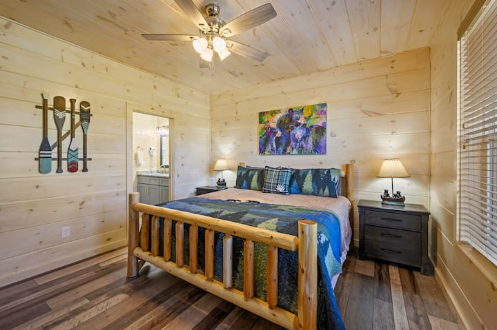 Dhomë gjumi e rehatshme në ambient me ndriçim të ngrohtë prej pelushi dhe prekje druri rustik që të fton të çlodhesh dhe të rigjenerohesh në stil me një banjë të plotë ngjitur