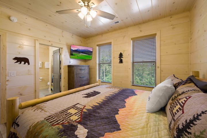 Dhomë gjumi e rehatshme në ambient me ndriçim të ngrohtë prej pelushi dhe prekje druri rustik që të fton të çlodhesh dhe të rigjenerohesh në stil me një banjë të plotë ngjitur