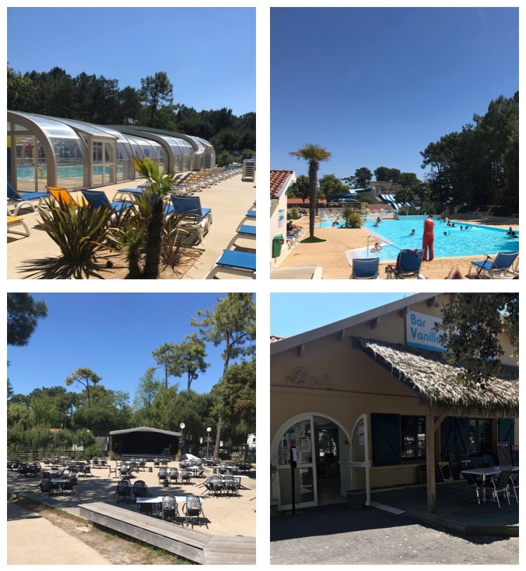 A clear blue sky provides a backdrop for a leisure area featuring a pool surrounded by sun loungers. Nearby, a bar with an outdoor seating space is visible, complemented by lush greenery and palm trees. The area exudes a relaxed vibe perfect for enjoying sunny days.