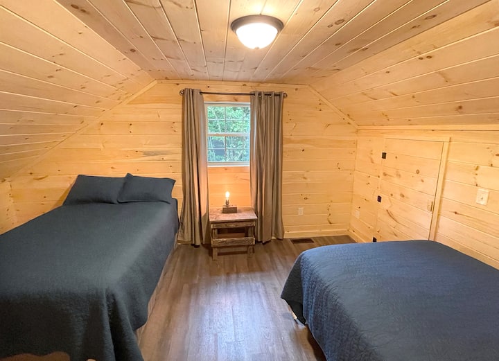 I call this the bunk room. It features two double beds and is located in the furthest corner of the second floor. It's a great space for kids to bunk up, play games, and go to bed early if necessary without being disturbed by activity downstairs.