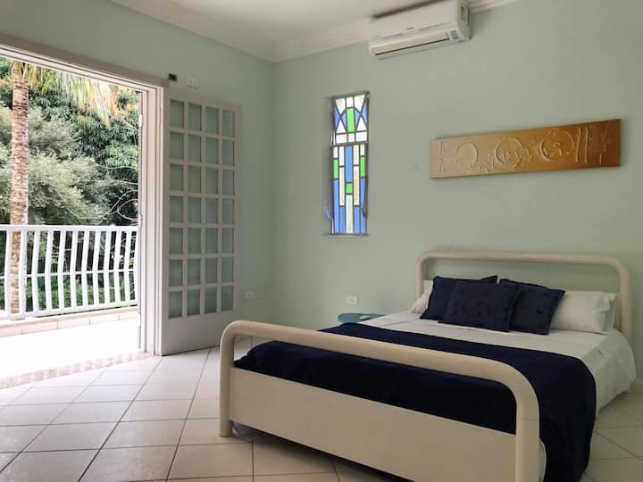 2号套房-上层-配备1张标准双人床、1张单人辅助床、空调、衣柜和阳台，可俯瞰泳池和绿色区域。