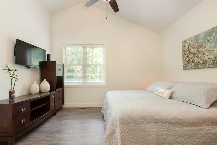 The main bedroom has a comfortable king-size bed, a vaulted ceiling, smart TV, and a private bathroom.
