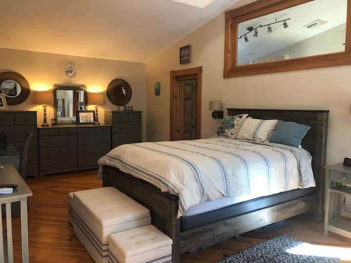 Chumba kikuu cha kulala (kitanda cha ukubwa wa Malkia); bafu limeunganishwa.  Inajumuisha televisheni kubwa iliyowekwa ukutani inayoangalia kitanda (nje ya mwonekano kwenye picha); kabati la kuingia.