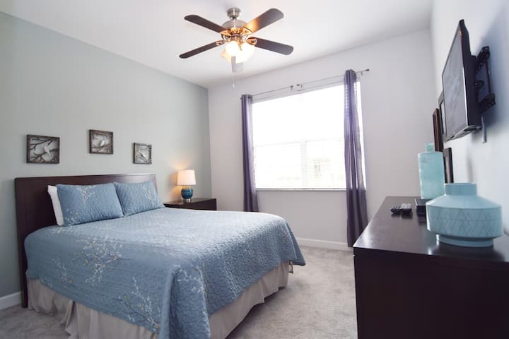 ห้องควีนไซส์ชั้นล่างพร้อมสมาร์ททีวีพัดลมเพดานและห้องน้ำอยู่ติดกัน