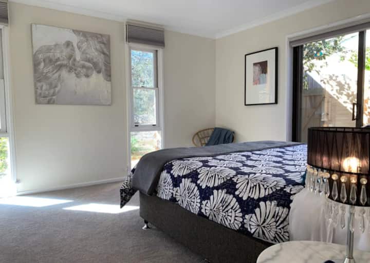 Chumba kikuu cha kulala kilichojaa mwanga na kitanda cha ukubwa wa kifalme.