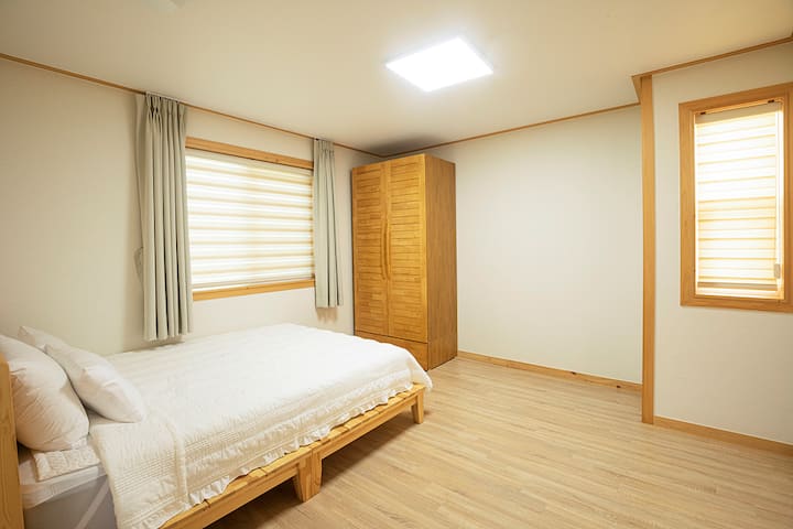 ห้องนอนชั้น 1 - เตียงควีนไซส์ตู้เสื้อผ้าโต๊ะเครื่องแป้งม่านทึบแสงห้องน้ำติดกับห้องนอน