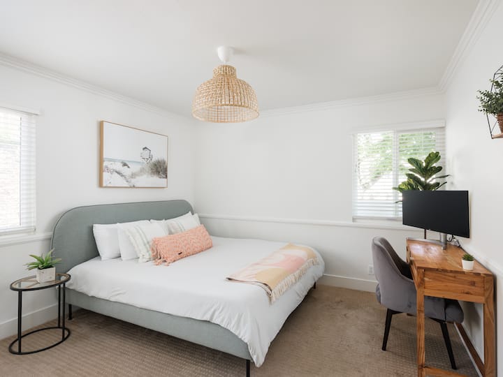 Chambre d'amis au rez-de-chaussée avec lit King Size et bureau avec grand moniteur.
