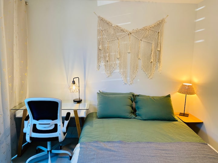 Una cama tamaño queen, una mesita de noche y un acogedor escritorio y una silla de jefe en el dormitorio del primer piso.