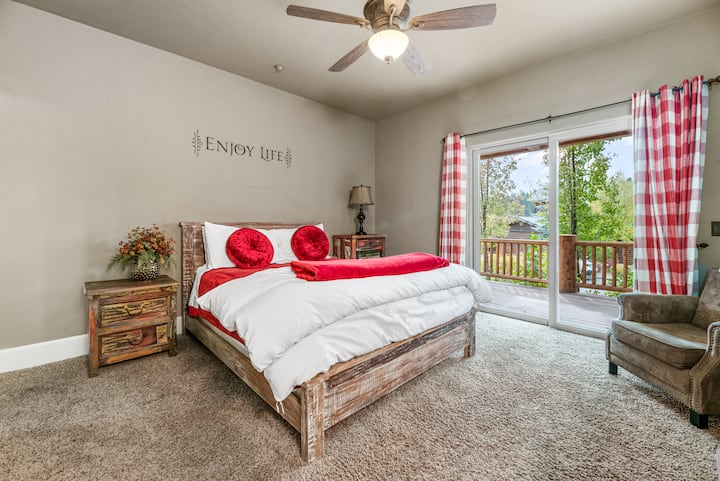 Bedroom 1, features a king-sized bed, a soothing "Enjoy Life" slogan, and a private balcony with a beautiful view, offering the perfect space to relax and unwind during your stay.