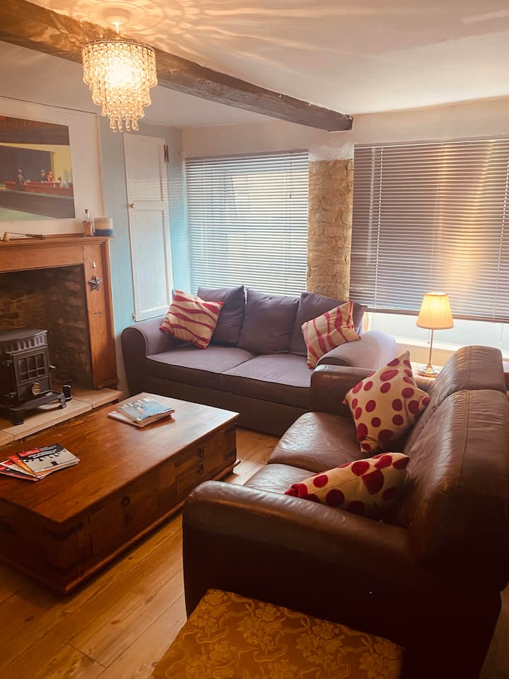 The main living is a cosy room with three sofas and a library of books