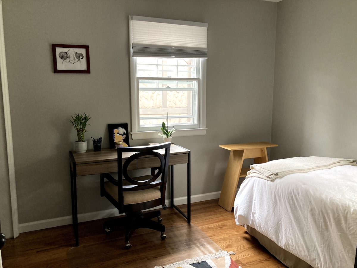 Cuarto dormitorio con área de trabajo y cama doble.