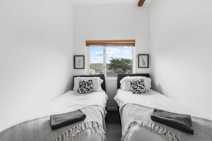 Un cómodo segundo dormitorio con dos camas individuales, perfecto para que los niños o amigos se relajen después de un día explorando Cornwall.