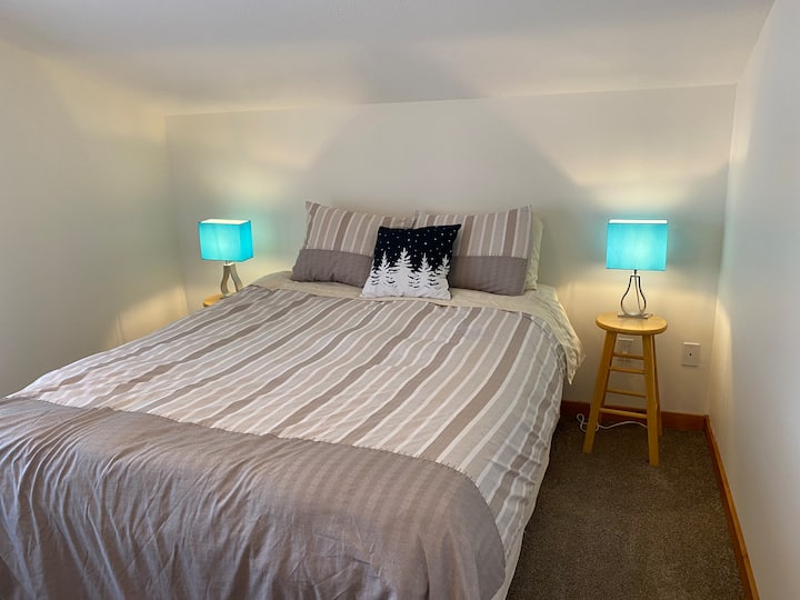 Druga spavaća soba uključuje ormar, komodu i bračni krevet s plišanim tepihom pod nogama.