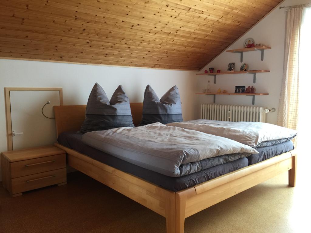 חדר שינה עם מיטה זוגית וחלון לצד המזרחי שטוף השמש