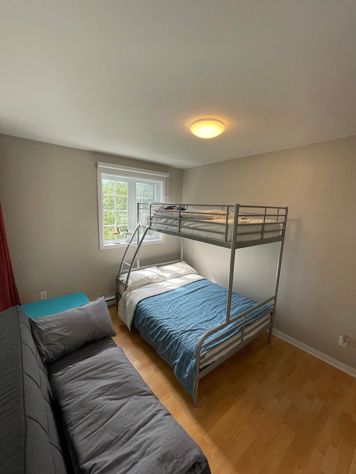 Le sofa gris s'ouvre (l'appui-tête/dos se plie vers le bas) pour devenir un lit.