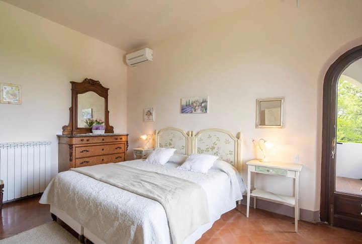 Disfruta de una estancia tranquila en este luminoso y espacioso dormitorio  con baño privado con sábanas acogedoras y hermosos muebles tradicionales, aire acondicionado ,con acceso a un balcón privado con vistas al paisaje de la campiña toscana.